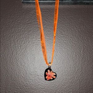 Orange ribbon necklace with black heart pendant.